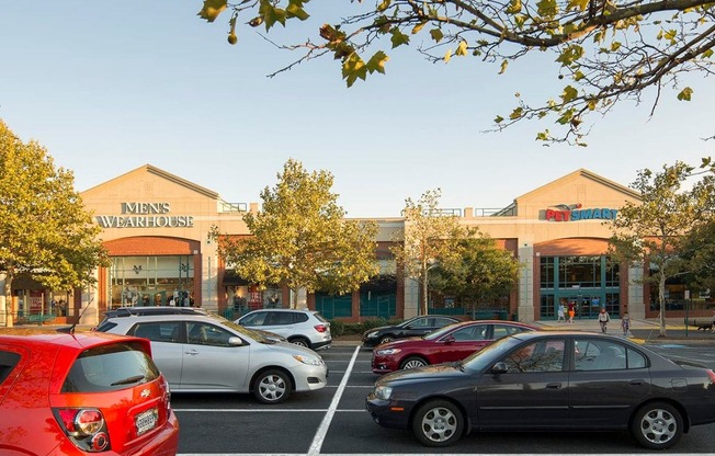 a parking lot filled with cars in front of a shopping center