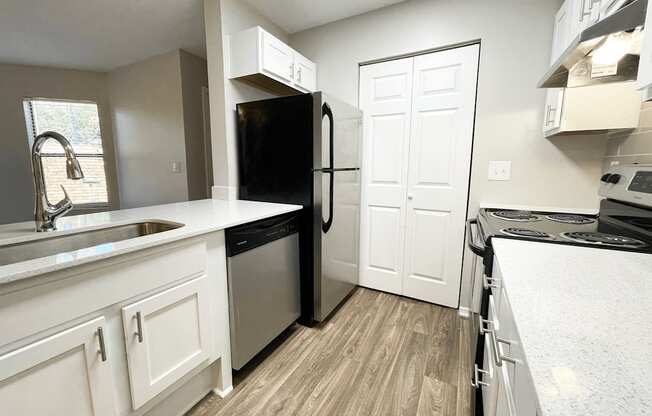 an empty kitchen with white cabinets and a black refrigerator