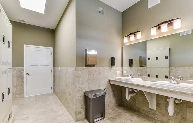 a bathroom with two sinks and a trash can