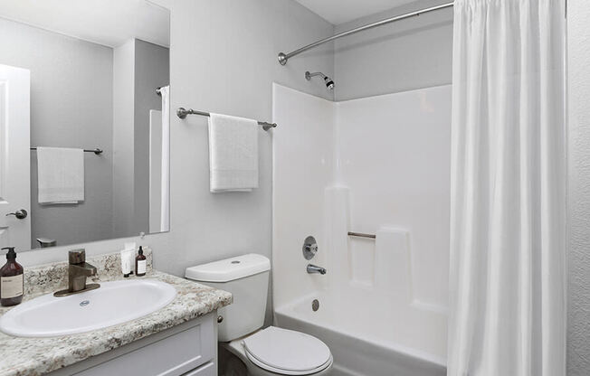 Model Bathroom with White Cabinets, Wood-Style Flooring and Shower/Tub at The Meritage Apartments in Vallejo, CA.