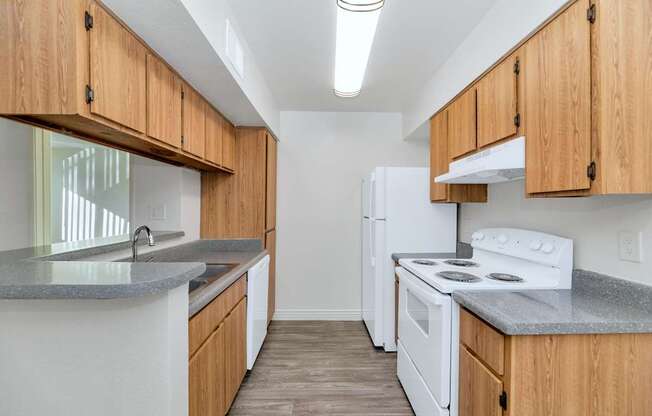 A kitchen with white appliances and wooden cabinets at Urban WalkApartments on 6th Avenue, Phoenix, Arizona