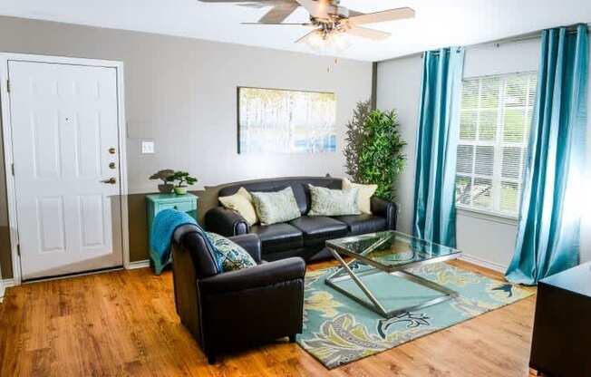 A living room with a black couch and a glass coffee table.