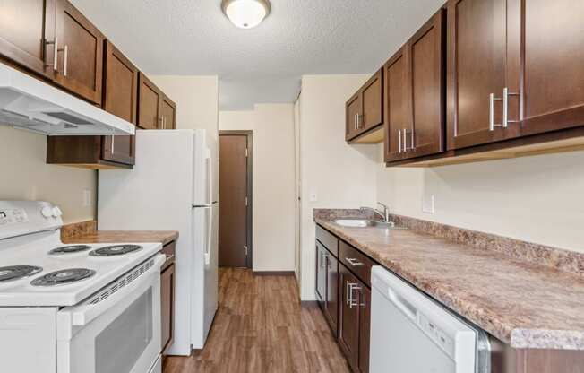 an empty kitchen with white appliances and wooden cabinets