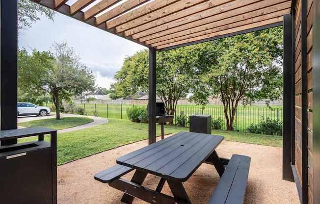 A picnic table is under a wooden canopy.