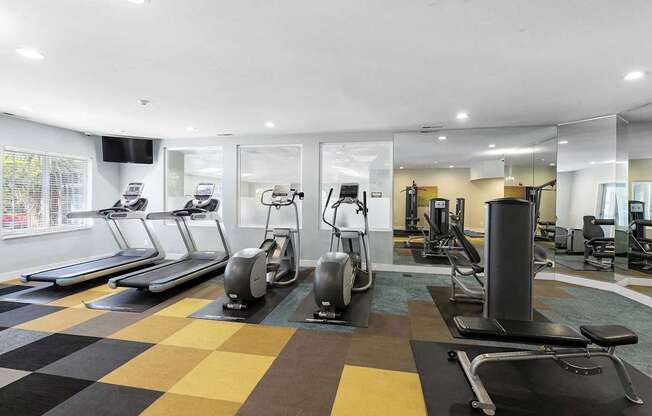 A gym with treadmills, elliptical machines, and other exercise equipment.