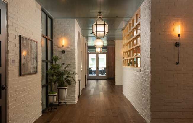 Long white brick hallway with wood flooring and geometric pendant lighting leading to resident lounge at Sylvan Uptown, Colorado