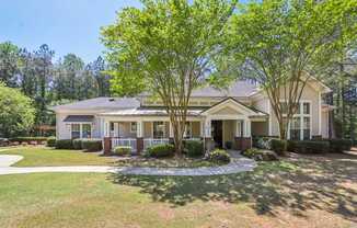 A house with a front yard and a tree in front.