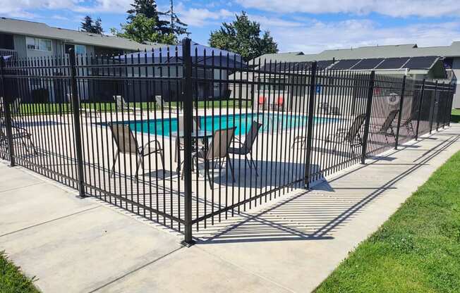 a wrought iron fence around a pool with patio furniture