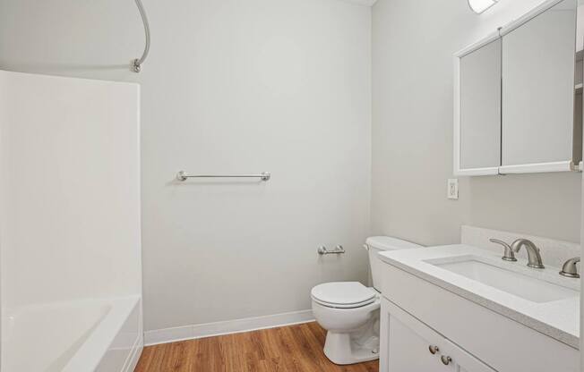 A white bathroom with a toilet, sink, and a shower.