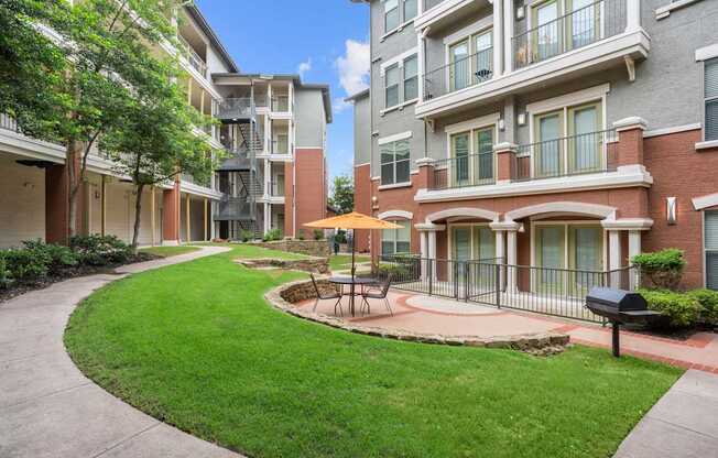 A sunny day at a residential complex with a green lawn and a small fountain.