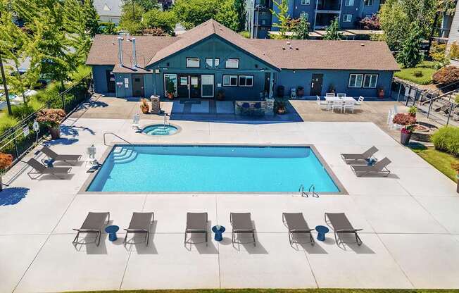 A pool with lounge chairs and a building in the background.