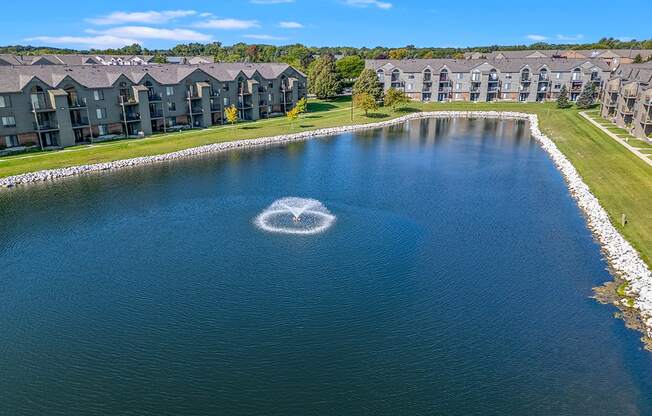 A large pond with a fountain in the middle at Oak Shores Apartments in Oak Creek, WI