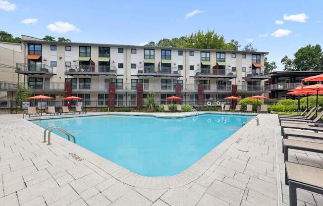 A large swimming pool in front of a multi-story apartment building.