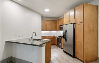 Kitchen with stainless steel appliances and wooden cabinets at The Monterey by Windsor, Dallas, Texas