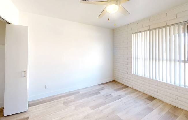 A room with a ceiling fan and a window with blinds.