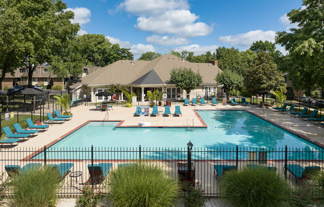 A pool surrounded by chairs and trees.