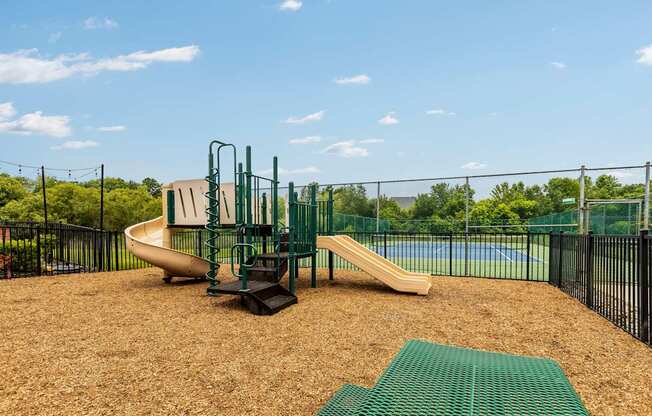 A playground with a slide and a green mat.