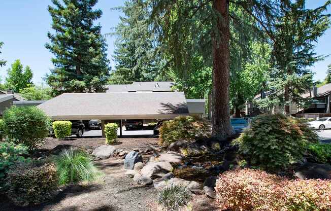 A house with a grey roof is surrounded by trees and plants.