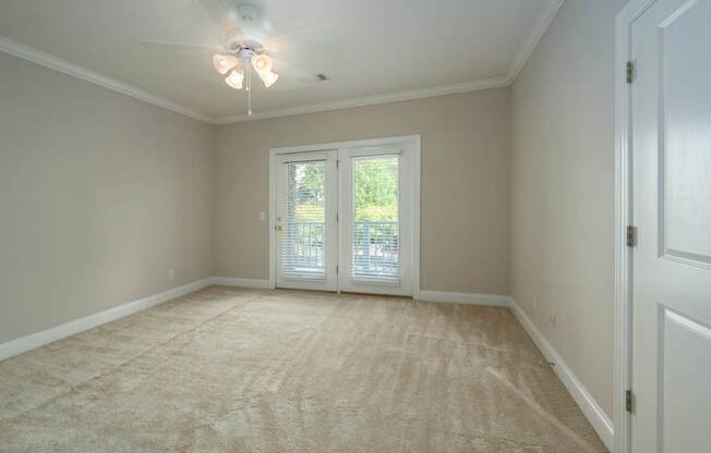 A room with a carpeted floor and a ceiling fan.