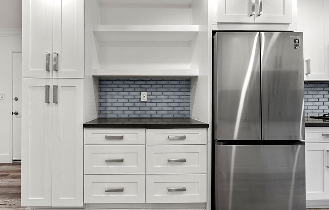 Stainless steel fridge adjacent shelving and storage cabinetry.