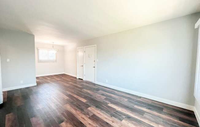 an empty living room with wood floors and white walls