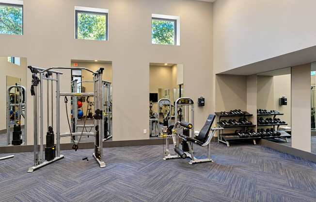 Fitness center with strength training machines, a weight bench and dumbbells at Icon Avondale Apartments in Decatur, GA.