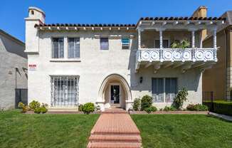 a white house with a balcony and a green lawn