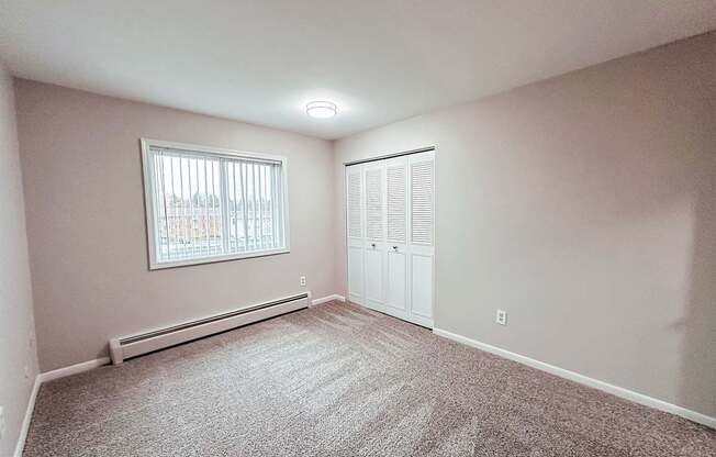 A room with a window and a carpeted floor.
