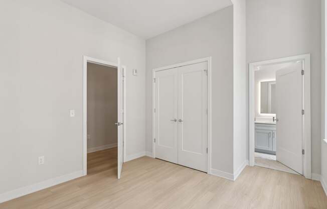 A white room with a wooden floor and three doors.