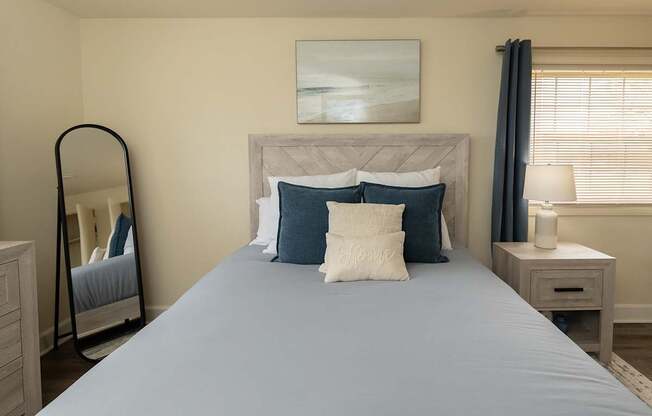 A bed with a grey sheet and two pillows is in the center of the room.