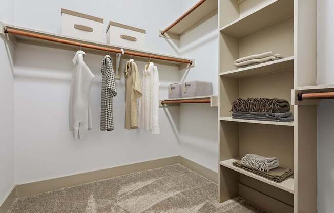 A white and beige laundry room with clothes hanging and folded on shelves.
