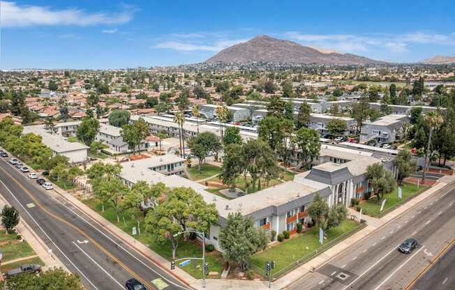A city street with cars and buildings with a mountain in the background.
