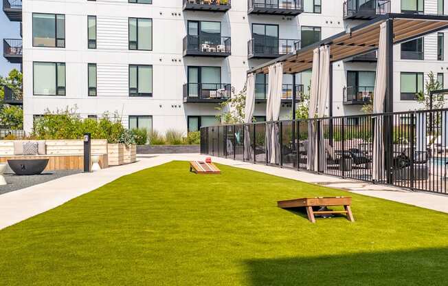 a grassy area with two benches in front of an apartment building