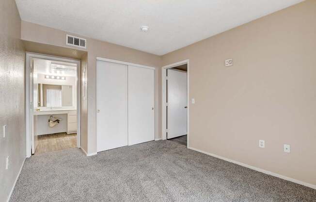 A spacious room with a grey carpet and white doors.