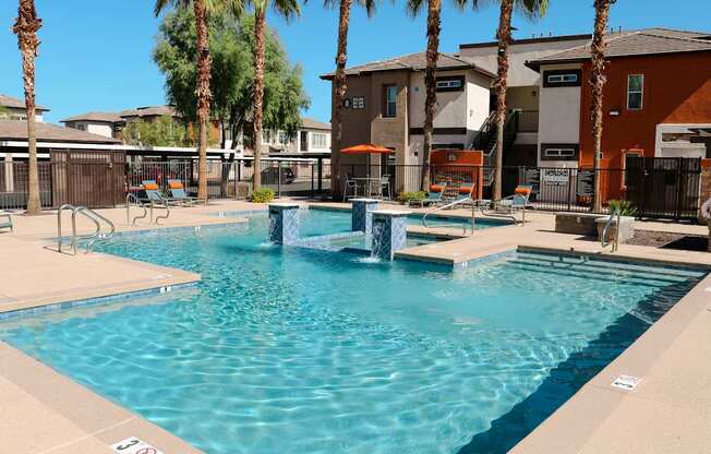 A swimming pool surrounded by palm trees and apartment buildings.