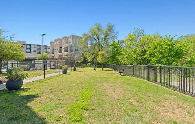 A park with a fence and a bench in front of a building.