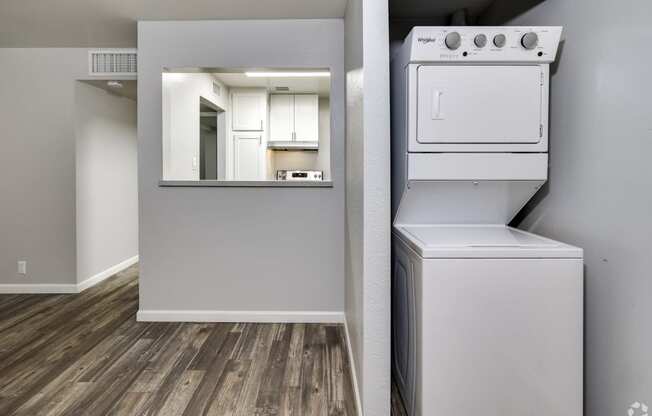 an empty apartment with a washer and dryer and a kitchen