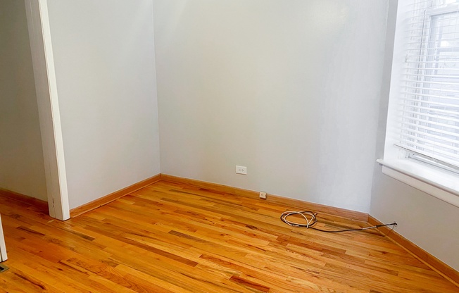 an empty room with wooden flooring and two windows