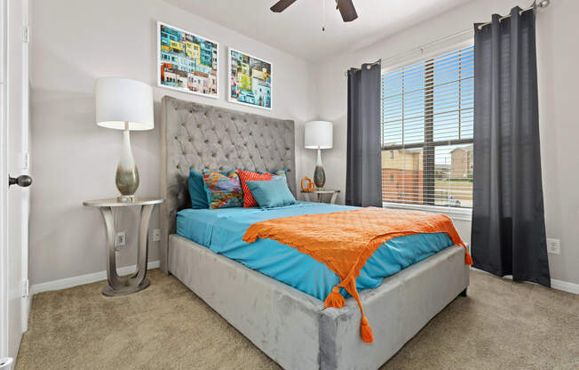 a bedroom with a bed with an orange blanket and blue pillows