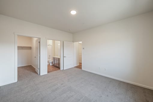 a living room with white walls and carpet and a door to a bathroom at Gateway Apartments, Washington