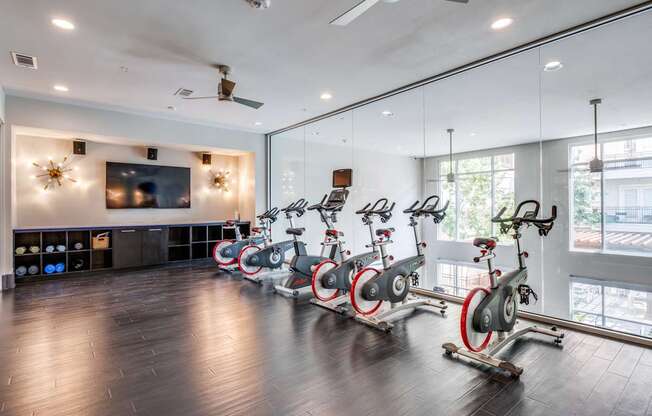 a fitness room with spin bikes and a tv