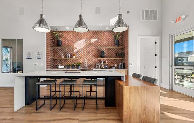 A kitchen with a long table and chairs with pendant lights hanging above it.