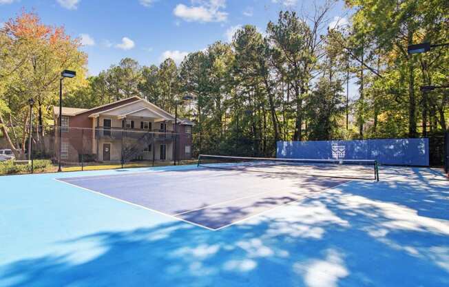 Blue tennis court with apartment building in the background at Oakley Run apartments in Smyrna, GA