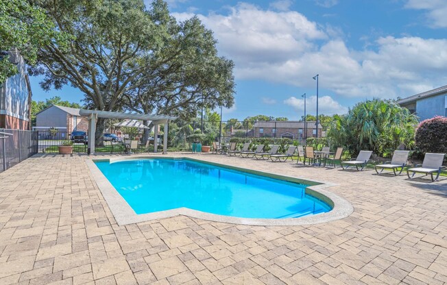 A swimming pool surrounded by a brick patio and lounge chairs at Magnolia Apartments in Shreveport, LA