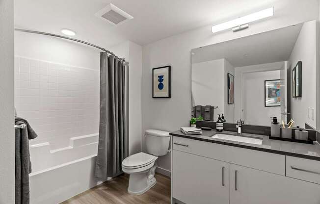 A white bathroom with a toilet, sink, and shower.