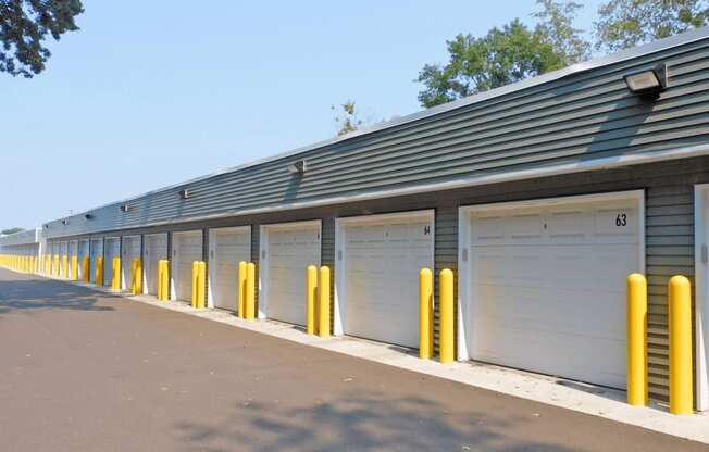 a row of garages with white doors and yellow posts