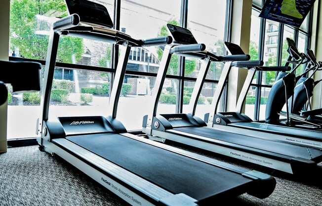 two treadmills in a gym with a large window