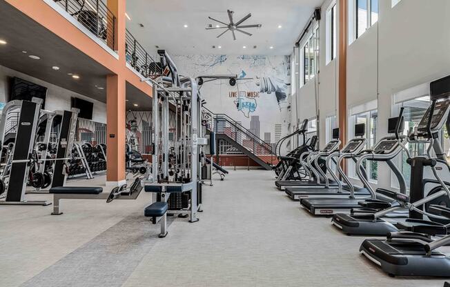 a gym with cardio equipment and a mural on the wall