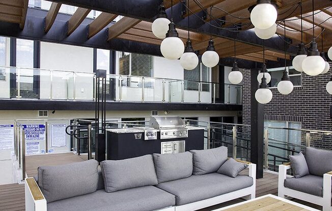 A modern outdoor seating area with grey couches and wooden tables.