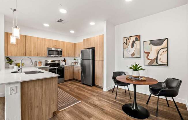 A modern kitchen with a wooden counter and black chairs.